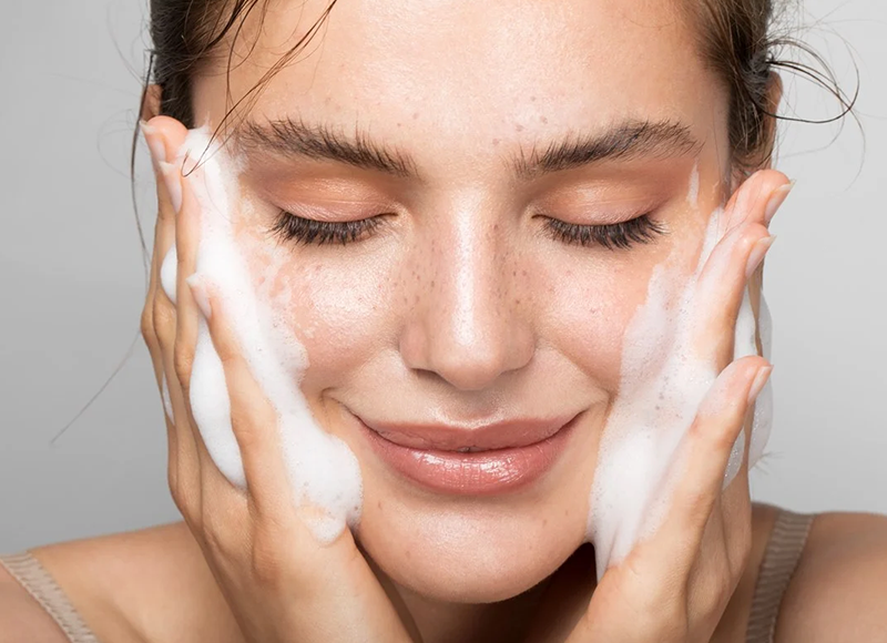 Imagem de uma mulher branca lavando o seu rosto.