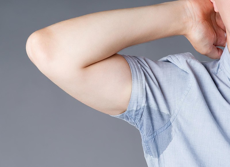 Imagem de um braço levantado mostrando a mancha de suor na camiseta