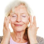 Imagem de uma mulher de idade fazendo massagem facial.