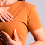Imagem de um corpo feminino, com as duas mãos examinando um dos seios.